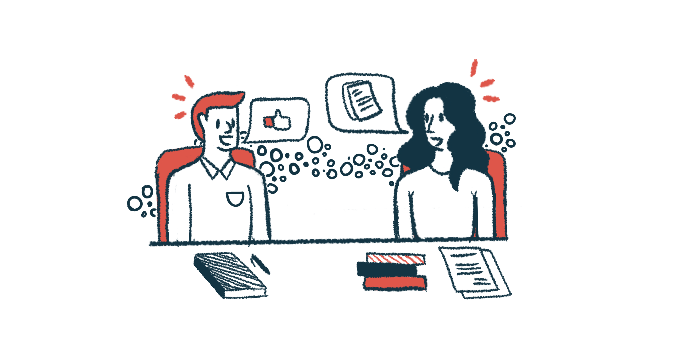 Two people are seen having a discussion during a meeting, with notebooks and papers on the table in front of them.